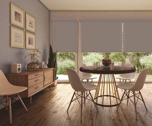 Living room with large windows, white roller shades, wooden sideboard, round dining table, four white chairs
